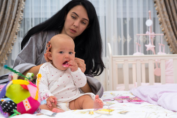 Young careful mother dressing baby in the morning