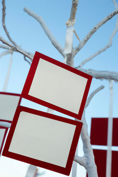 Segna posto bianchi con cornice rossa appesi ad un albero