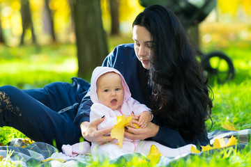 Laughing little baby playing with fall leaves