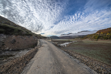 Old road in ruins that is generally flooded by the waters of the reservoir of Riaño in Leon, Spain. In the background you see the mountains between the morning mists. 