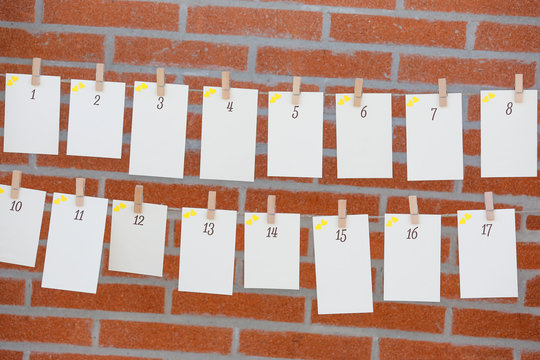 Biglietti numerati appesi a un filo con delle mollette- sfondo muro con mattoni 