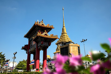 Fototapeta premium Architectural detail of Buddhist temple, Wat Traimit and Chinatown Gate over blue sky in Bangkok, Thailand