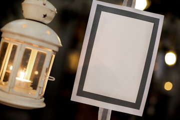 Segna posto bianco appeso con lanterna affianco