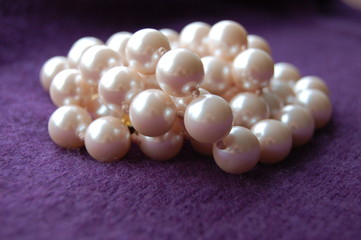 Jumbled strung pearls on purple cashmere background