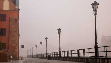 A promenade along the riverbank of Motlawa River in Gdansk, Poland. Misty and foggy weather.
