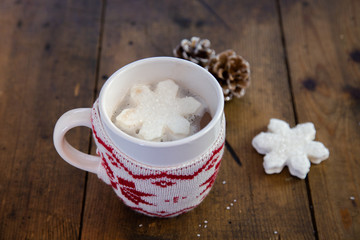 Mug of hot chocolate with a snowflake marshmallow on a wooden counter