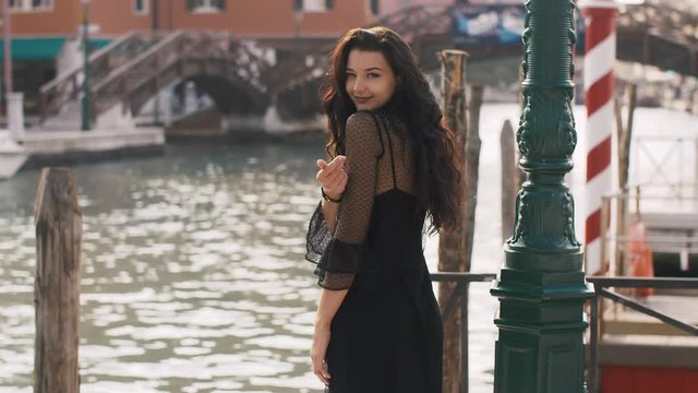 Romantic tourist woman standing on the pier against beautiful view on venetian chanal with boats and gondolas in Venice, Italy. Stunning slow motion 4k footage. Gorgeous mixed race Asian Caucasian
