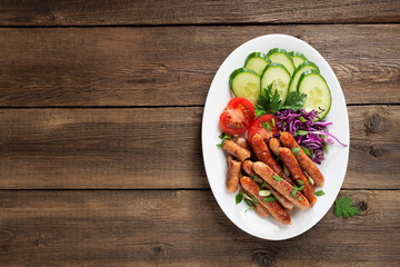Tasty grilled sausages with vegetable salad in white plate
