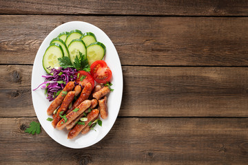 Tasty grilled sausages with vegetable salad in white plate