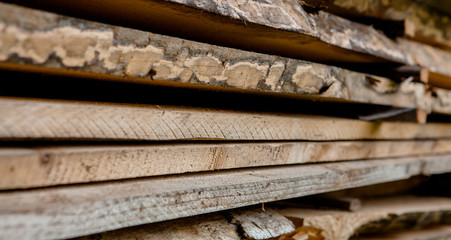 Folded wooden brown and gray planks in a sawmill. Piled alder boards as texture