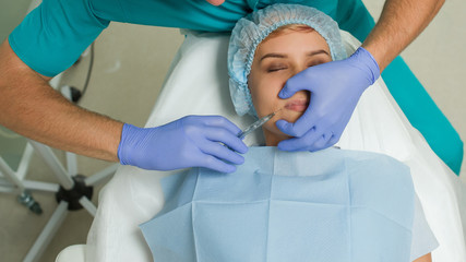 Top view of lips augmentation procedure on a young woman done by a cosmetologist doctor with...