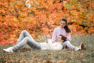 couple in love sitting in autumn park and reading book