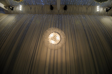 Chandelier hanging under a ceiling in a wedding restaurant by night