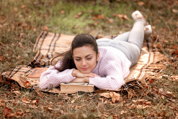 Fototapeta premium woman sitting in autumn park and reading book
