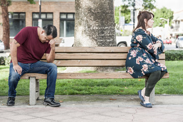 Unhappy Mixed Race Couple Sitting Facing Away From Each Other on Park Bench