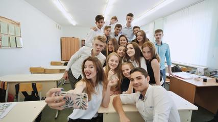 Young happy cheerful students making selfie in school class.