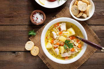 Chicken soup with noodles and vegetables in white bowl on  wooden background