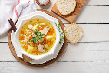 Chicken soup with noodles and vegetables in white bowl on white  wooden background