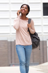 happy young black woman walking and talking with mobile phone