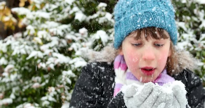 Young Girl Blowing Handful Of Winter Snow At Camera In Slow Motion