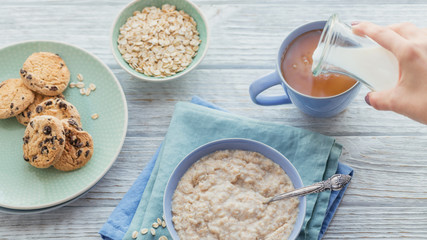 Oatmeal porridge bowl on the white wooden background.