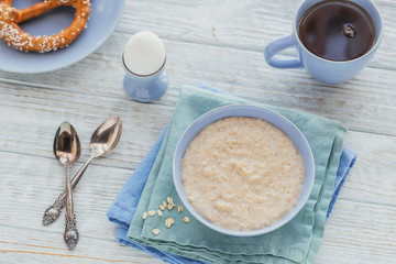 Oatmeal porridge bowl on the white wooden background.