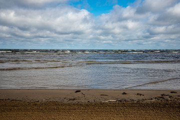 empty sea beach in spring with some birds and cargo ships on the horizon