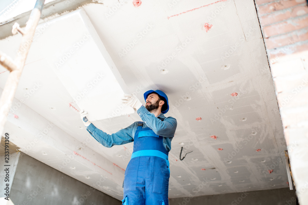 Wall mural builder warming building ceiling mounting foam panels on the construction site