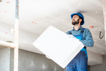 Builder warming building ceiling mounting foam panels on the construction site