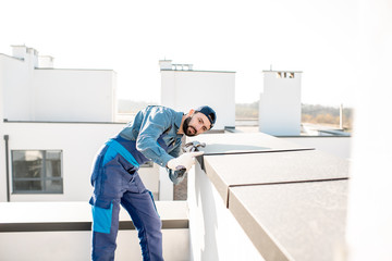 Builder in uniform mounting metal cover on the parapet of a new building