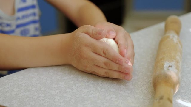 Children's rolling pin for dough. The child kneads the dough with his hands.