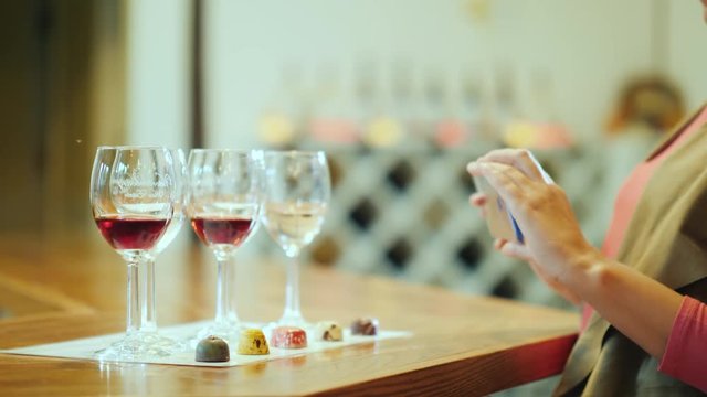 A woman photographs a series of glasses and beautiful candy. Wine tasting with sweets and wine tour
