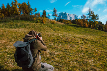 young adventure explorer and photographer tourist taking landscape picture of pelmo mountain in alps dolomites in autumn sunny day