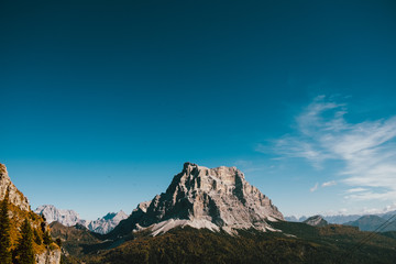 landscape view of majestic rocky mountain eleventing from woods with dramatic blue sky