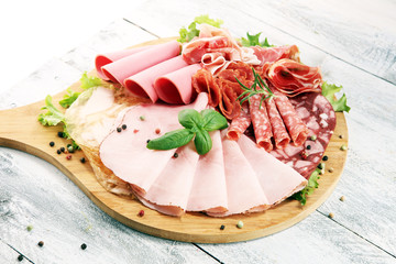Food tray with delicious salami, pieces of sliced ham, sausage and salad. Meat platter with selection.