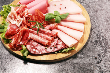 Food tray with delicious salami, pieces of sliced ham, sausage and salad. Meat platter with selection.