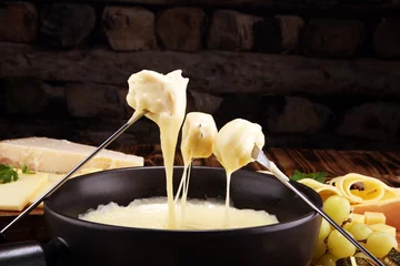 Fototapeten Gourmet Swiss fondue dinner on a winter evening with assorted cheese © beats_
