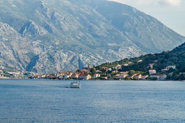 Fototapeta na wymiar The city on the beach at the foot of the high mountains in the Bay of Kotor