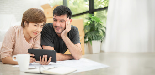 Couple with digital tablet and blueprints planning their new moving house.