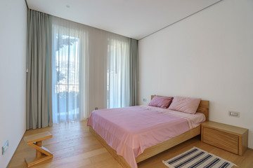 Interior of a spacious light bedroom with windows in a luxury villa