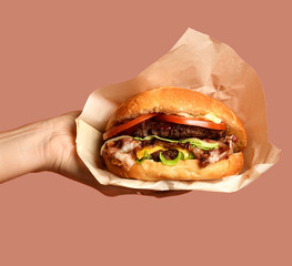 Woman hands hold big cheese burger barbeque sandwich with marble beef on orange 