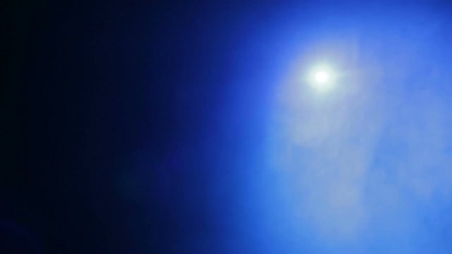 Scene illumination with a blue light beam of a spotlight in smoke from a smoke machine