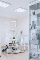 Dental treatment room with modern green chair, white tone. Orthodontic chair in small stomatology cabinet. Dental office.