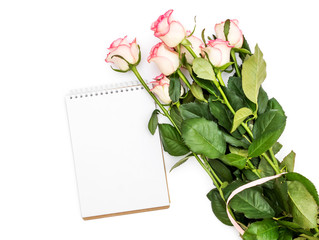 Bunch of roses with blank notepad on white.