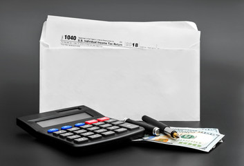 Calculator with money and envelope with tax form on black background.