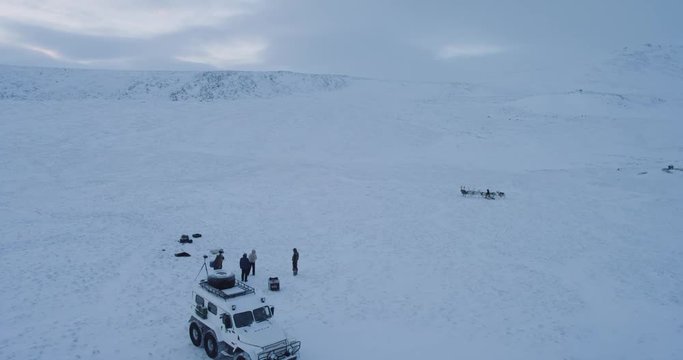 Arctic video capturing from drone of a big yurts camp , man ride on reindeers, around are a big snow machine and a video camera.