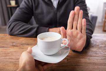 Man Refusing Cup Of Coffee Offered By Person