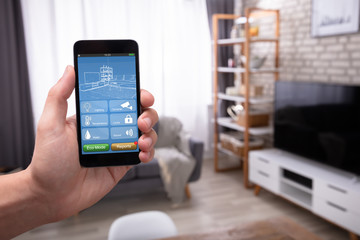 Man Using Smart Home Application On Mobile Phone