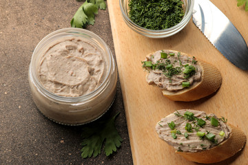 Fresh homemade chicken liver pate with greens on bread on a dark background. A sandwich.