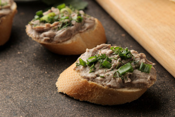 Fresh homemade chicken liver pate with greens on bread on a dark background. A sandwich. close-up